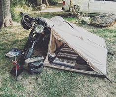 a motorcycle parked next to a tent in the grass