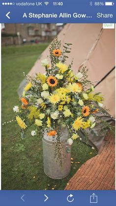 a vase filled with yellow and white flowers sitting on top of a grass covered field