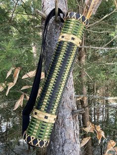 a green and black bag hanging from the side of a tree