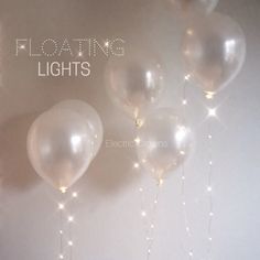 several balloons with string lights hanging from the ceiling in front of a wall that says floating lights