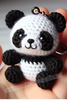 a small crocheted panda bear keychain is held in someone's hand