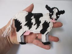 a hand holding a small black and white cow ornament in it's palm