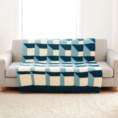 a blue and white blanket sitting on top of a couch in front of a window