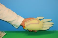 a person wearing white gloves is holding something in their left hand with yellow rubber fingertipss