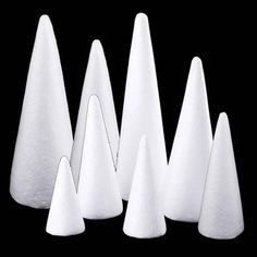 five white cones are lined up in the shape of three pyramids on a black background