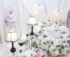 a baby crib is surrounded by white flowers and other decorations, including a teddy bear