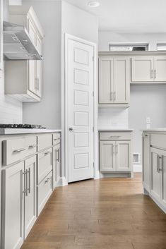 an empty kitchen with all white cabinets and wood flooring is pictured in this image