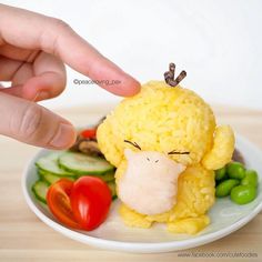 a person touching the face of a stuffed animal on top of a plate with vegetables