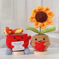 two small crocheted vases with flowers in them, one holding a heart