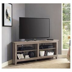 a flat screen tv sitting on top of a wooden entertainment center next to a window