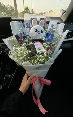 someone is holding a bouquet with pictures and flowers in the back seat of a car