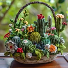 a basket filled with crocheted cacti sitting on top of a wooden table