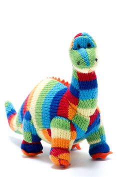 a colorful knitted toy dinosaur on a white background with clippings to the side