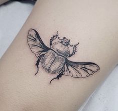 a black and white photo of a beetle tattoo on the right thigh, with an insect sitting on it's back