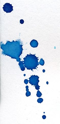 blue ink splattered on white paper with watercolors in the bottom right corner