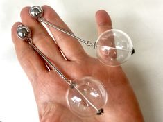 "Vintage 80s shoulder duster dangle earrings featuring polished platinum silver tone bars and extra large transparent glass bubbles with silver tone caps suspended from polished round silver button clips. The diameter of the transparent large bubbles are 3 cm (1.2\" ),the  silver hollow button clips are  1.2 cm (0.5\")  the total length is 10.5 cm (4.1 \") weight 18 gr, in excellent vintage condition (NOS from Italy) Because of the size of the bubbles they must be dispatched as a small package ( instead of a large letter ) with accordingly higher shipping costs. For more vintage jewellery please visit my Etsy shop: http://vintageviomar.etsy.com SHIPPING To UK -Royal Mail 1st Class (delivery aim 2 days) To EU-Royal Mail International Tracked and Signed ( delivery aim 5 -7 days) To Everywher Modernist Earrings, Cocktail Earrings, Clip On Earring, Haute Couture Runway, Silver Button, Couture Runway, Silver Buttons, Big Earrings, Gold Glass