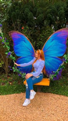 a woman sitting on a bench with a blue butterfly wings