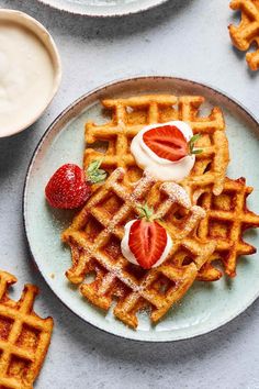 waffles with strawberries and whipped cream on them are arranged on a plate