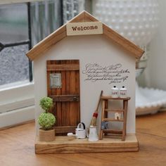 a miniature house with a welcome sign on the door and window sill next to it