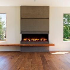 an empty room with wood floors and a fire place in the center, surrounded by windows