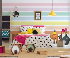 a bedroom with colorful striped wallpaper and bed in the corner, along with other decor items