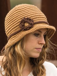 a woman wearing a brown hat with a flower on the front and side of her head