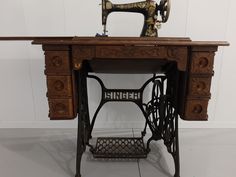 an old sewing machine sitting on top of a wooden table next to a white wall