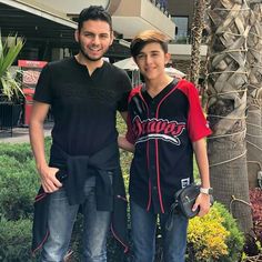 a man standing next to a boy in a baseball uniform