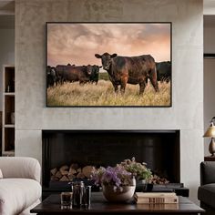 a cow is standing in the middle of a living room with a fireplace and large painting on the wall