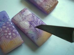 a pair of scissors sitting on top of some purple and white items with flowers painted on them