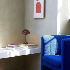 a blue chair sitting next to a white table with a lamp on top of it