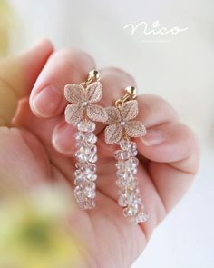 a pair of earrings with flowers hanging from it's ear wires in the palm of someone's hand