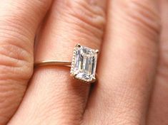 a close up of a person's hand with an engagement ring on their finger