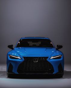 the front end of a blue sports car in a dark room with light from behind