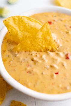 a tortilla chip being dipped into a bowl of quesadilla cheese dip