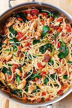 pasta with chicken, spinach and tomato sauce in a pan on a wooden table