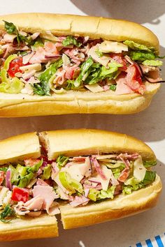 two sub sandwiches with meat, lettuce and tomatoes