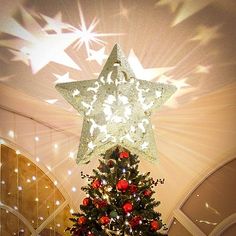 a decorated christmas tree in the middle of a room with stars on the ceiling above it