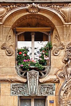 an ornate window with flower boxes on the ledge