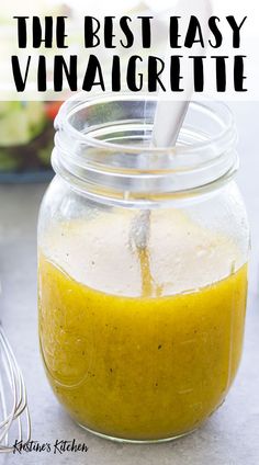 a glass jar filled with yellow liquid next to a whisk and other ingredients