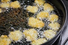 some food is cooking in a black pan on the stove top with water and oil