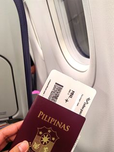 a person holding up a passport in front of an airplane window with the word philippines on it