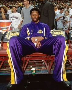 a man sitting on top of a bench in front of a crowd at a basketball game