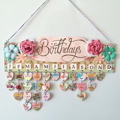 a birthday sign hanging from the side of a wall with hearts and flowers on it