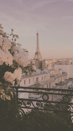 the eiffel tower is in the distance with white flowers on it's balcony