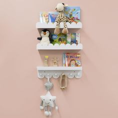 two white shelves with stuffed animals and books on them, against a pink wall in a children's room