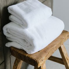 a stack of white towels sitting on top of a wooden stool