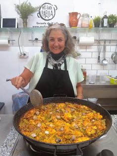 a woman is cooking food in a large pan