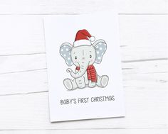 a baby's first christmas card with an elephant wearing a santa hat and scarf