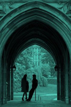 two people are standing under an archway